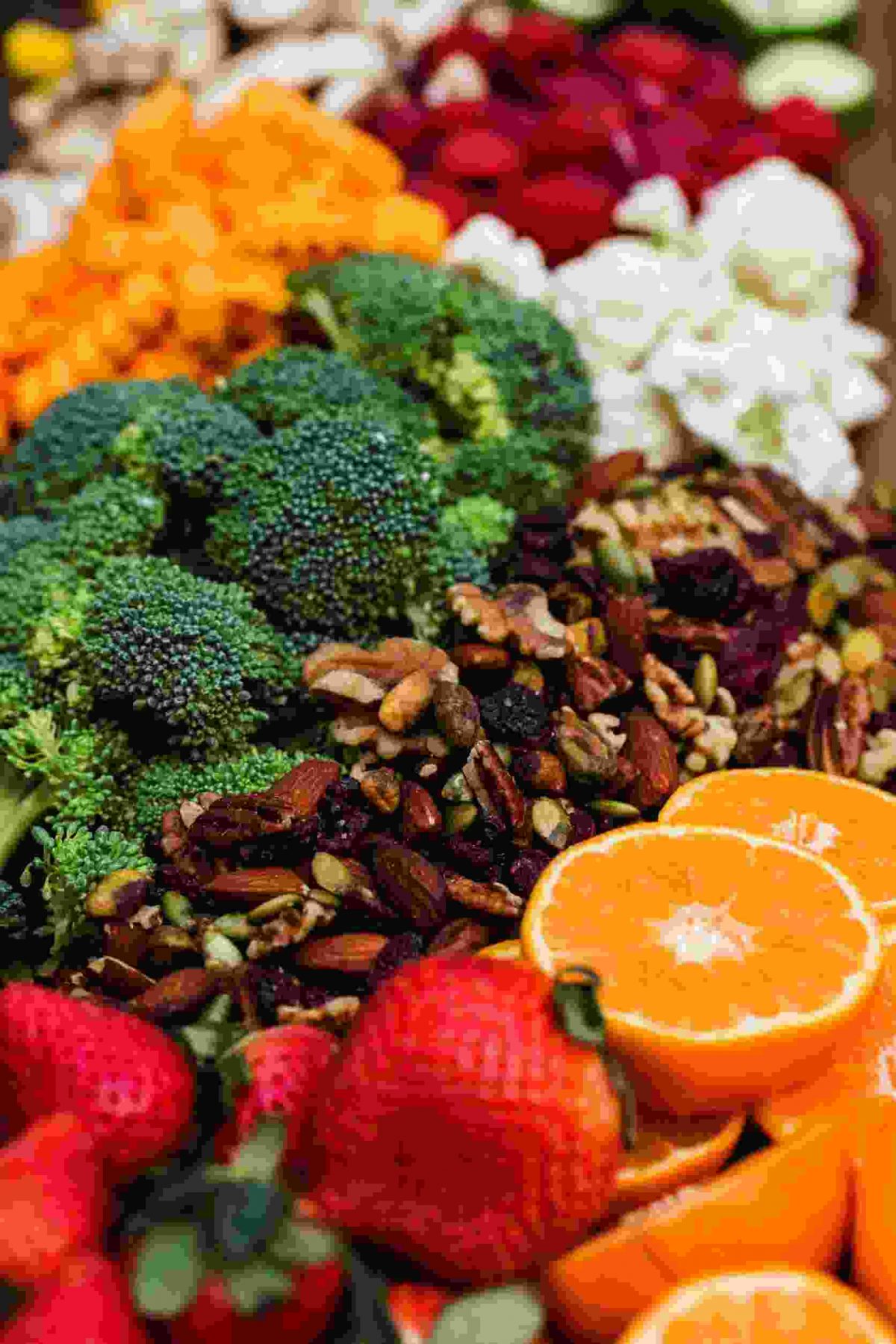 Hand holding vitamins and supplements with fresh berries, broccoli, peppers, and almonds in the background, highlighting the balance of whole foods and smart supplementation for fitness and health over 40.